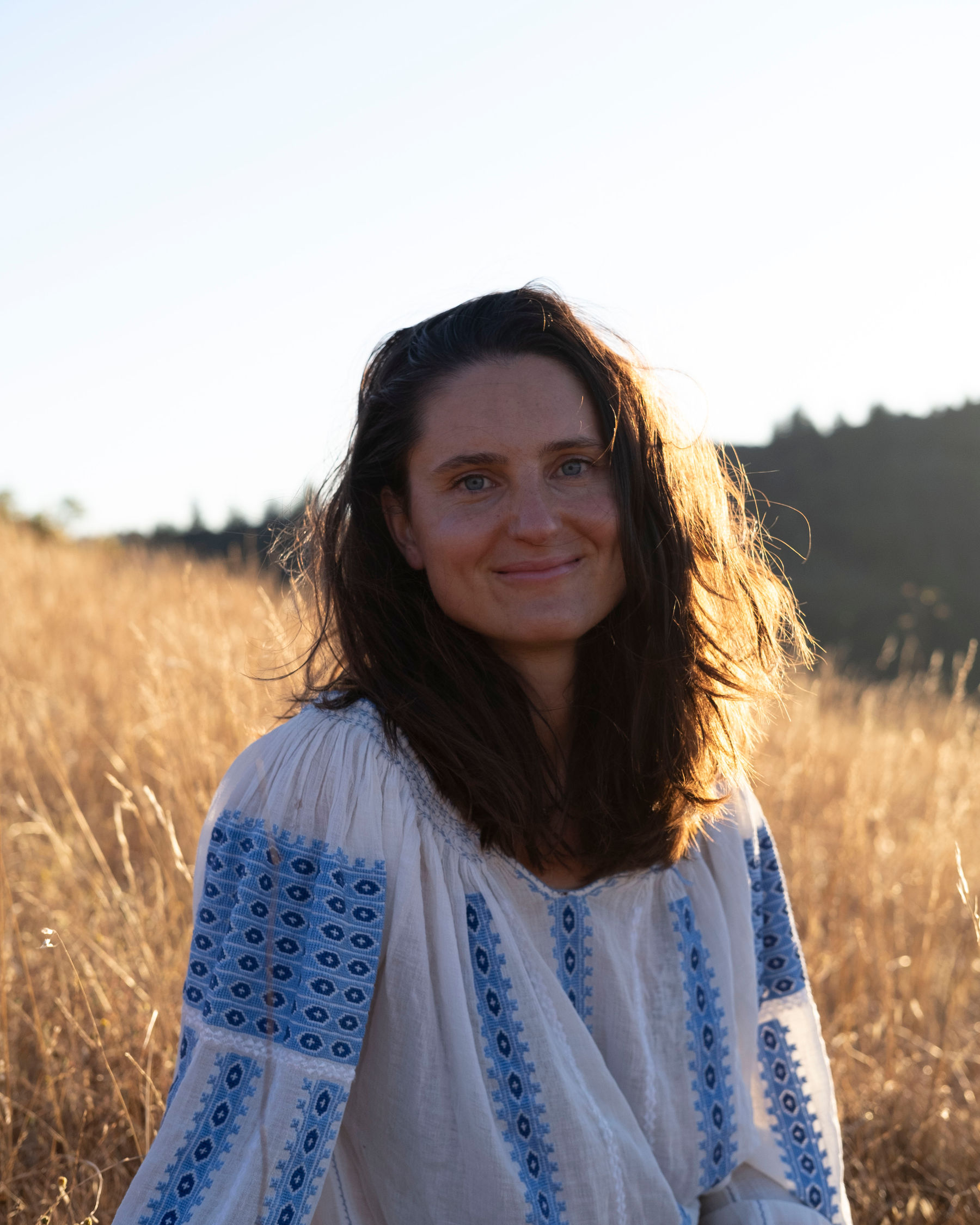 Portrait of Coco Borsche standing in a dry grass field in Marin County at sunset